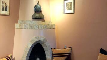 Una sala acogedora con chimenea de piedra, un banco acolchado y dos cuadros en la pared.