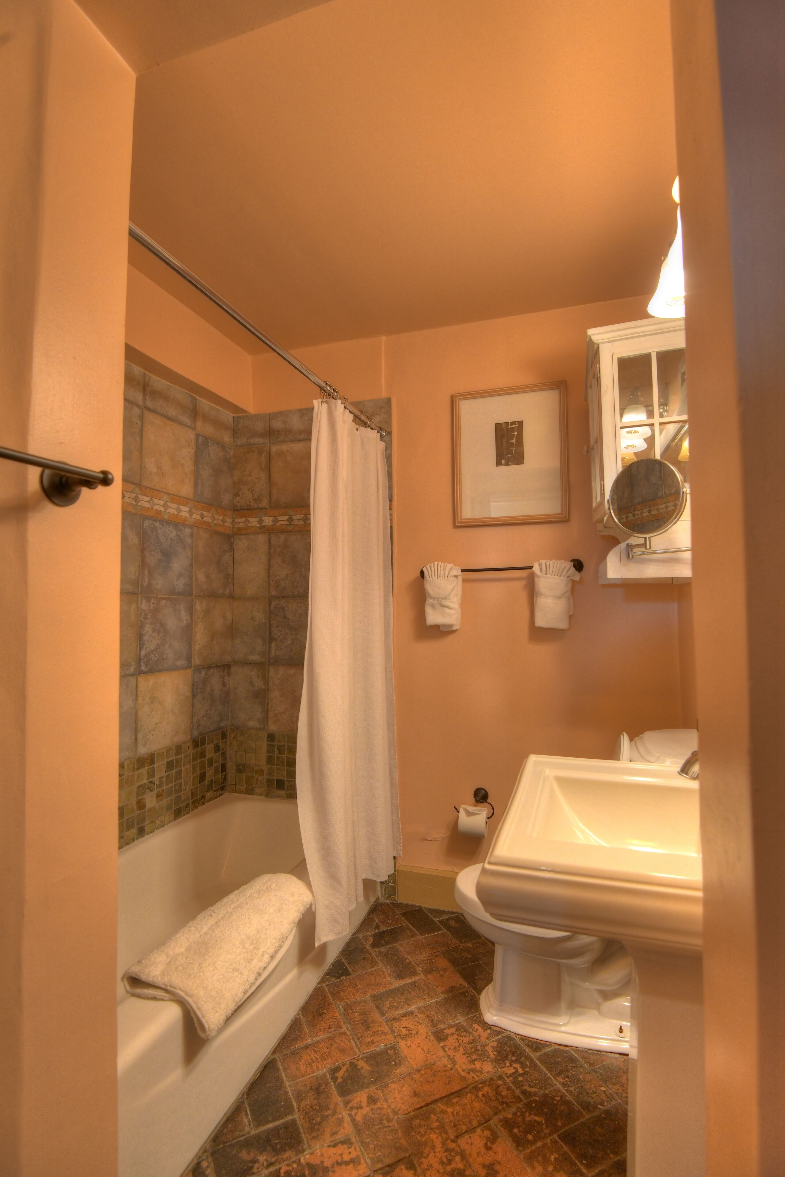 A bathroom with a bathtub, shower curtain, toilet, sink, and tiled floor.