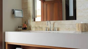 A bathroom with a large mirror, a white sink, and wooden shelves below.