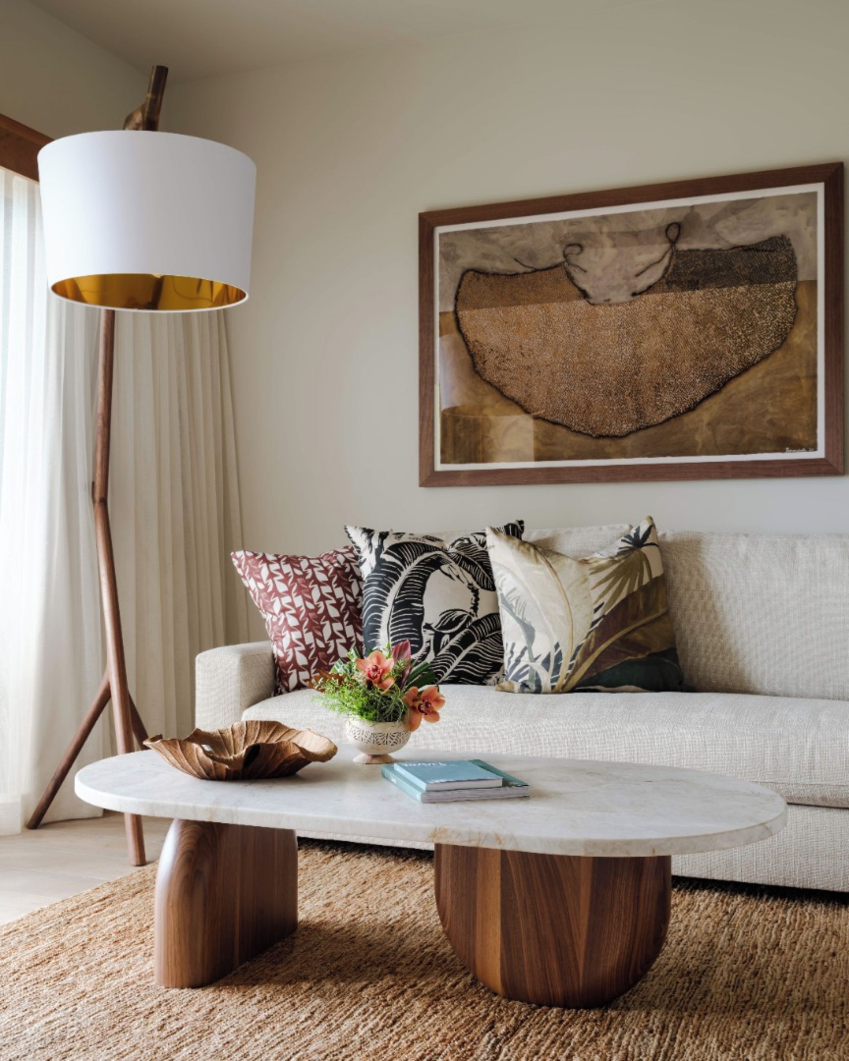 A living room with a sofa, a coffee table, a floor lamp, and a framed artwork on the wall.