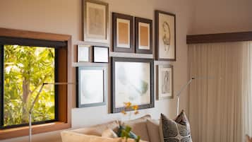 Een woonkamer met een groot raam, een bank en diverse ingelijste foto's aan de muur.