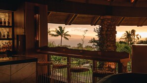 A bar area with a view of palm trees and the ocean at sunset. - Hotel Wailea, Relais & Chateaux - Adults Only (Kihei)