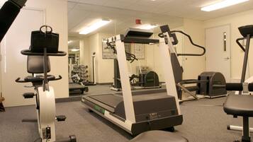 A gym with cardio machines, weight stations, and mirrors on the walls.
