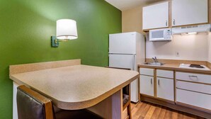 A compact kitchen with a green wall, a countertop, a refrigerator, a microwave, and a sink. - Extended Stay America Select Suites Tampa North Airport (Tampa)
