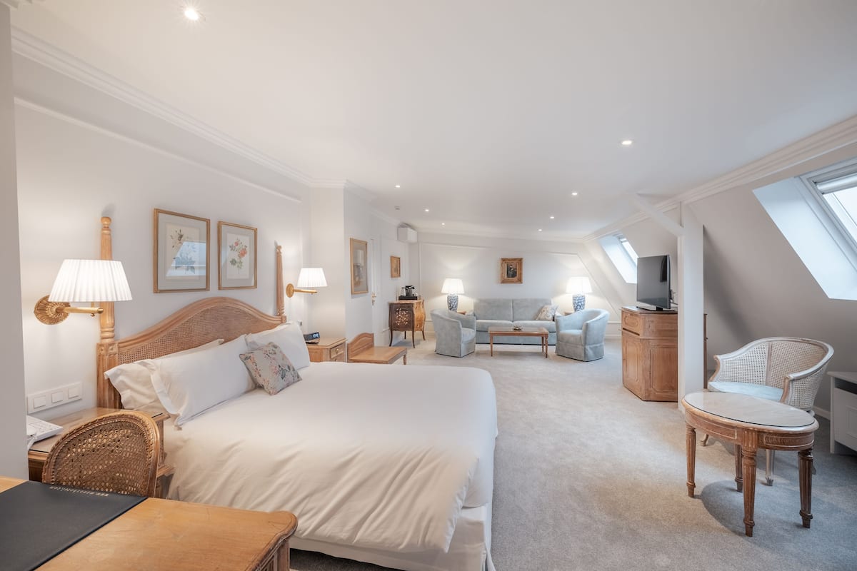 Une chambre d’hôtel avec un grand lit, un bureau, une chaise, un canapé et une télévision.
