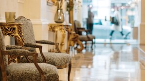 Un vestíbulo lujoso con candelabros ornamentales, muebles elegantes y un suelo reflectante.