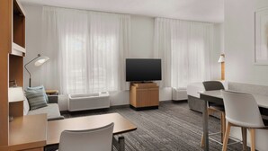 Een moderne hotelkamer met een flatscreen televisie, een bank, een eettafel en een stoel.