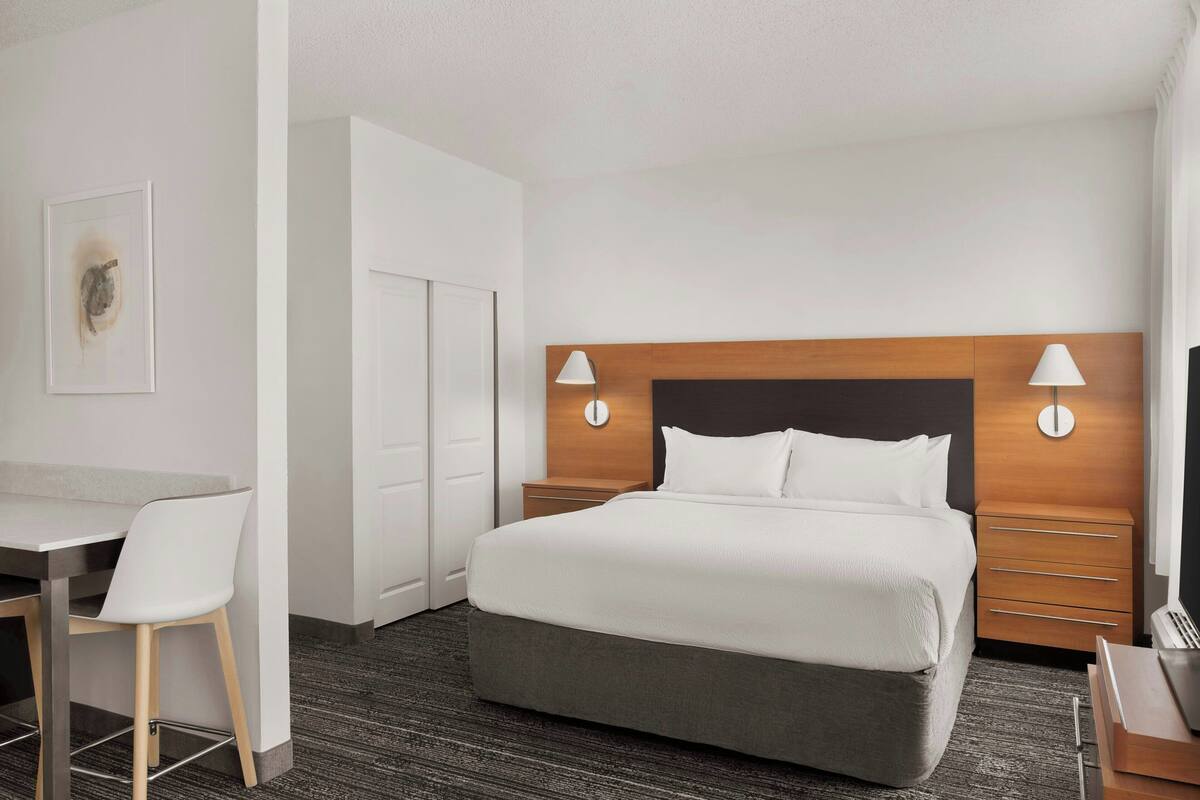A hotel room with a bed, bedside tables, a desk, and a chair.