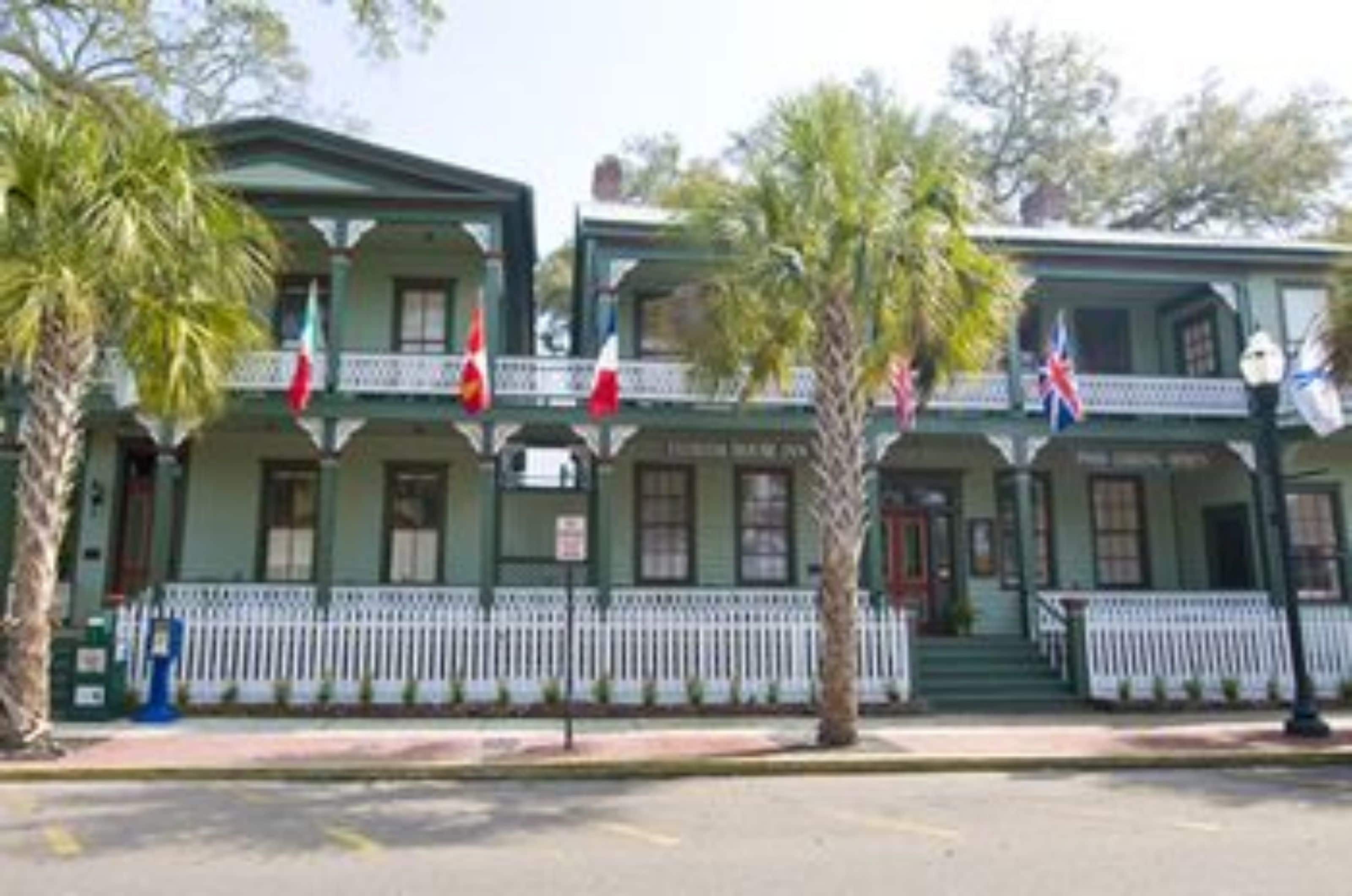 A two-story building with a balcony and a white picket fence.
