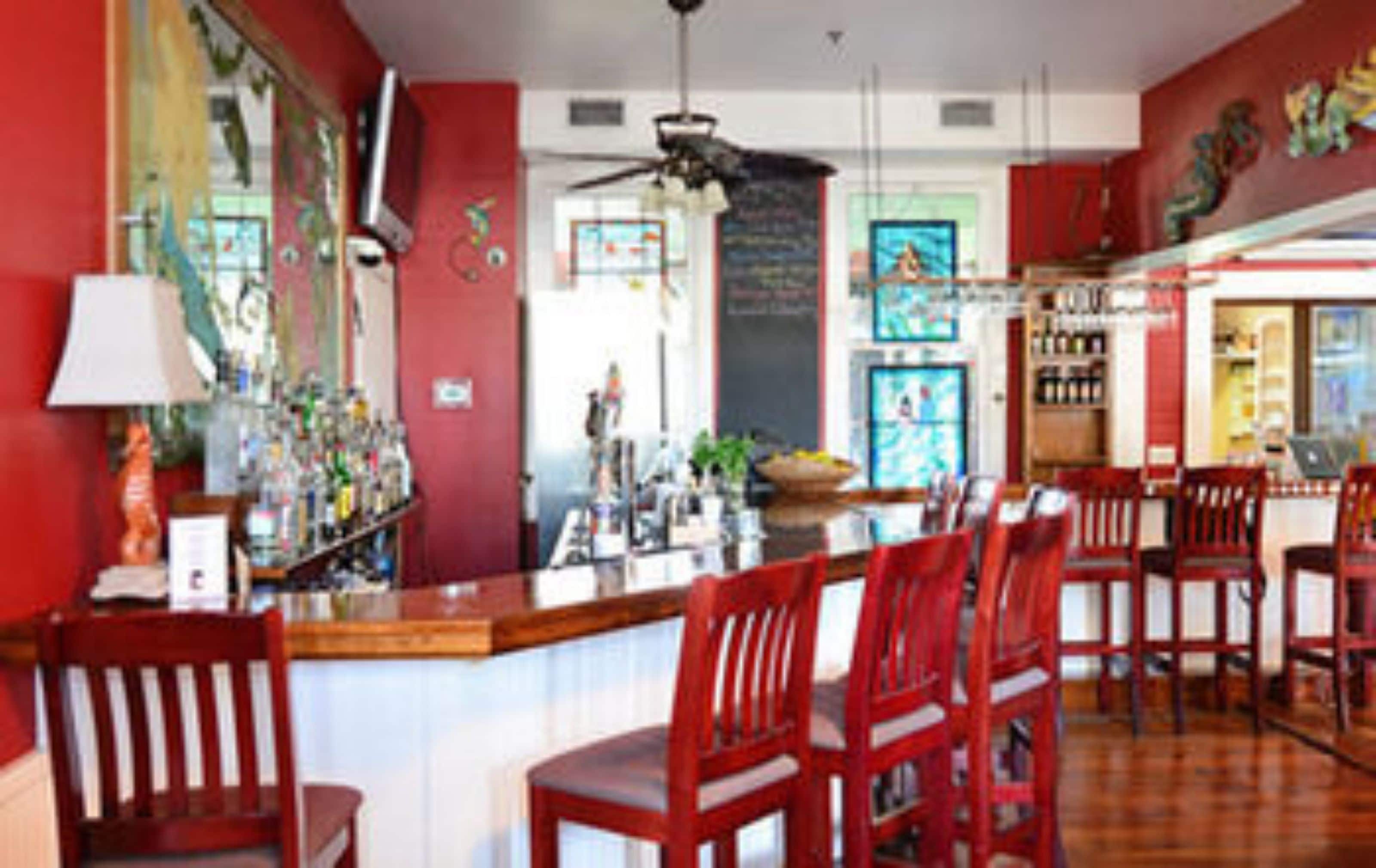 A restaurant with a red interior, wooden bar counter, and red bar stools.