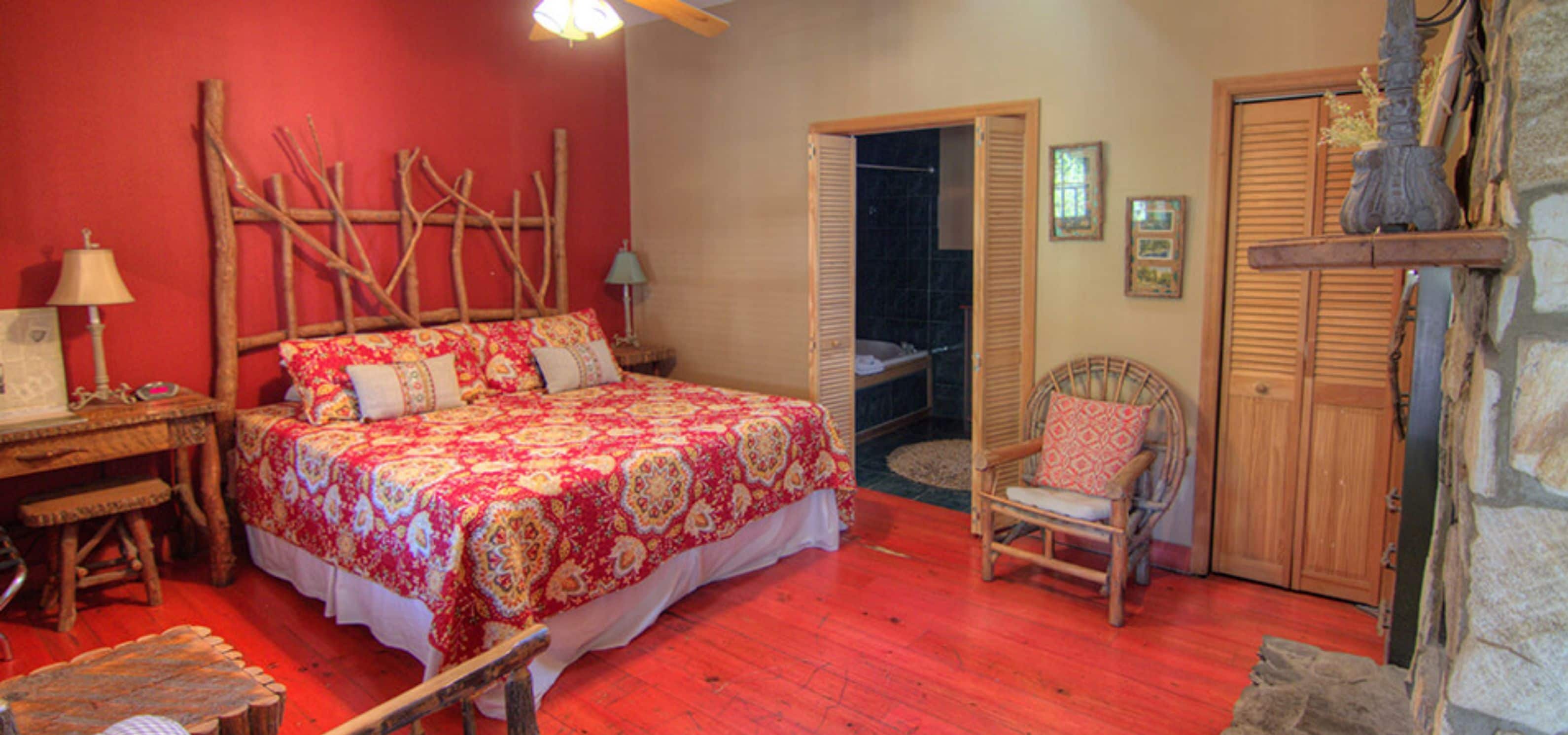 A bedroom with a bed, a chair, a wooden headboard, a nightstand, a lamp, and a wardrobe.