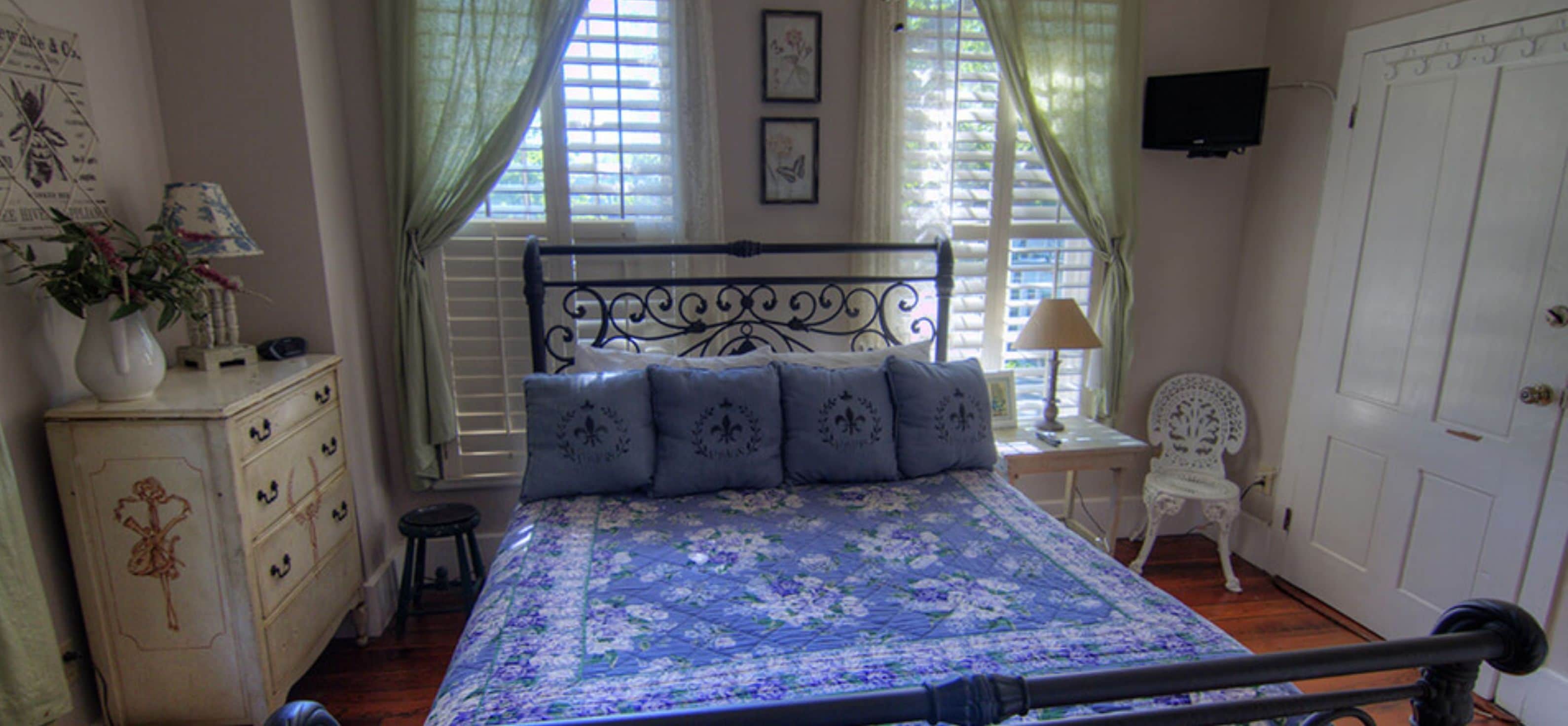 Une chambre à coucher avec un lit, une commode, une chaise et un téléviseur fixé au mur.