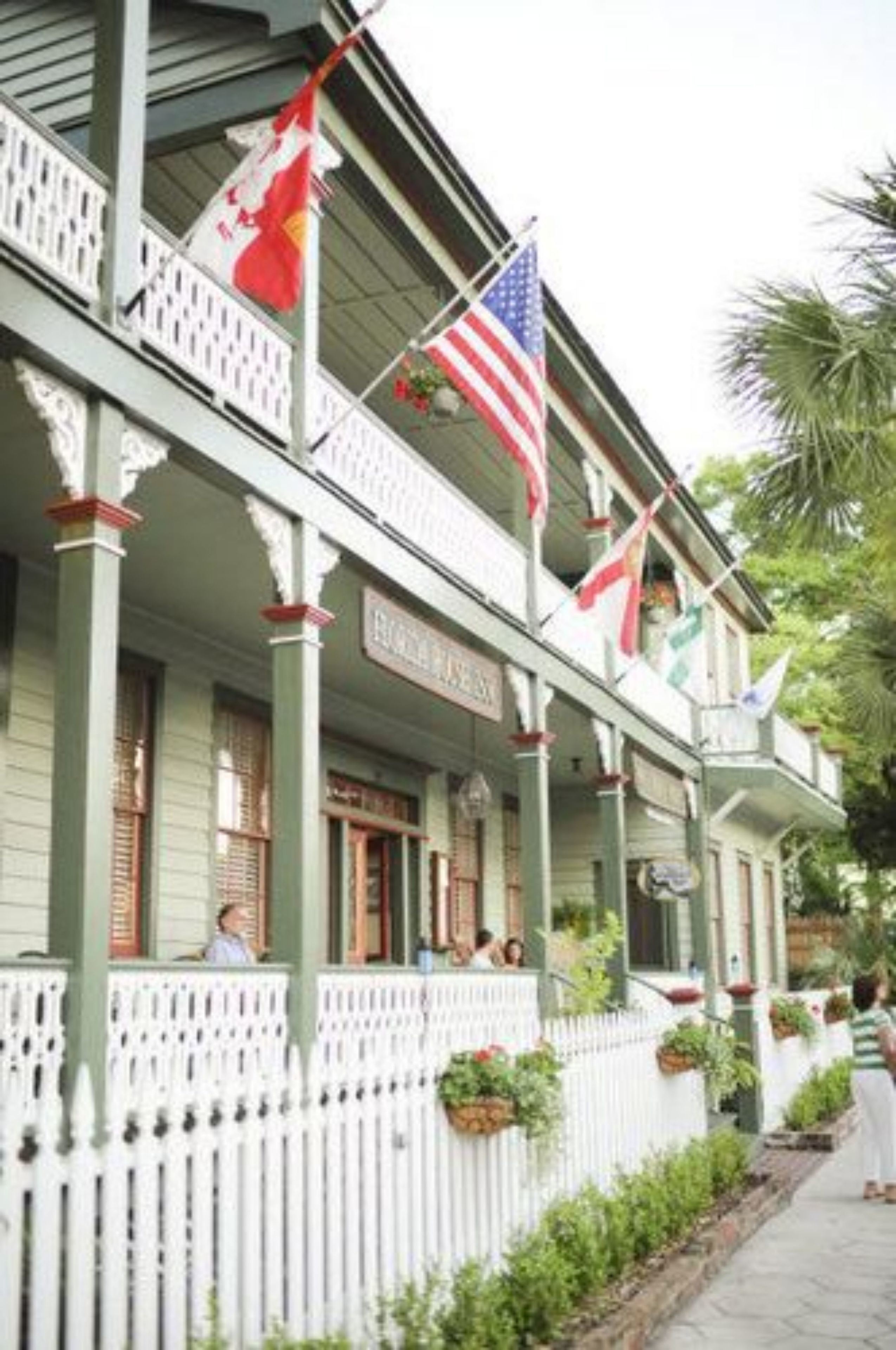 A building with a porch, flags, and a sign that reads "Hotel".