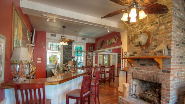 Eine Bar mit Holzsesseln, einem Kamin aus Ziegelsteinen und einem Deckenventilator.