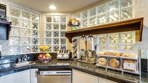 A kitchen with a built-in dishwasher, a fruit bowl, a toaster, and a bread display. - Monte Carlo Inn Toronto West Suites (Mississauga)