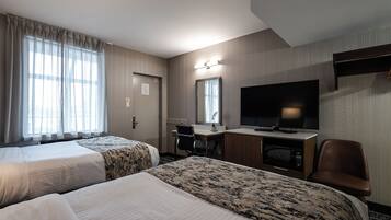 A hotel room with two beds, a desk, a TV, and a chair.