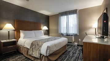 A hotel room with a large bed, two bedside tables with lamps, a TV, and a window with curtains.