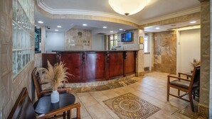 A hotel lobby with a reception desk, seating area, and a television screen. - Monte Carlo Inn Toronto West Suites (Mississauga)