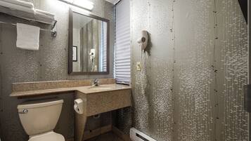 A bathroom with a toilet, sink, mirror, towel rack, and a hairdryer mounted on the wall.