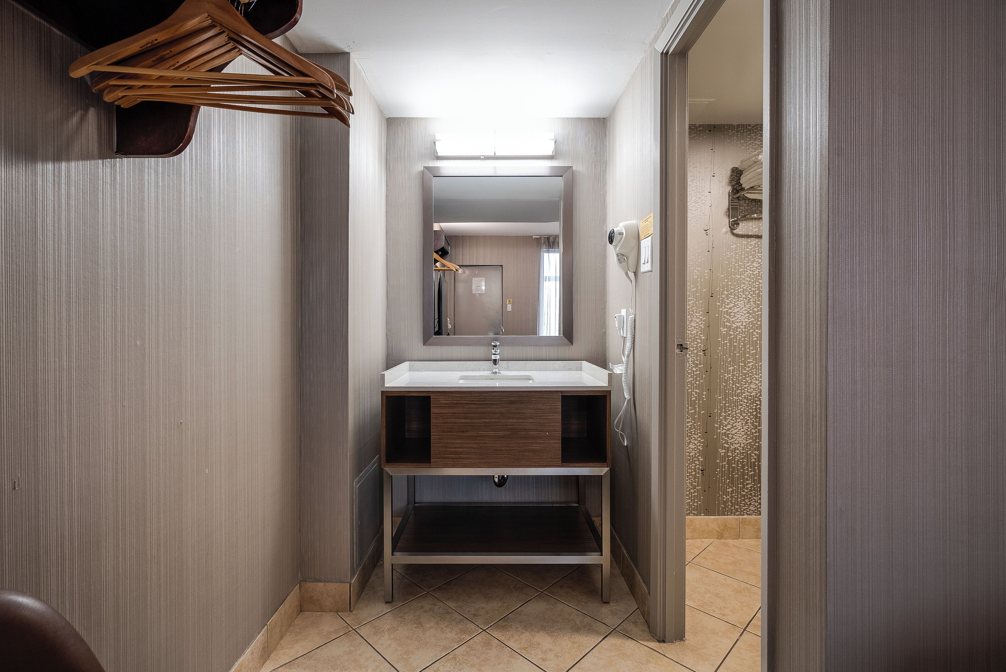 Een kleine badkamer met een wastafel, spiegel en houten planken.