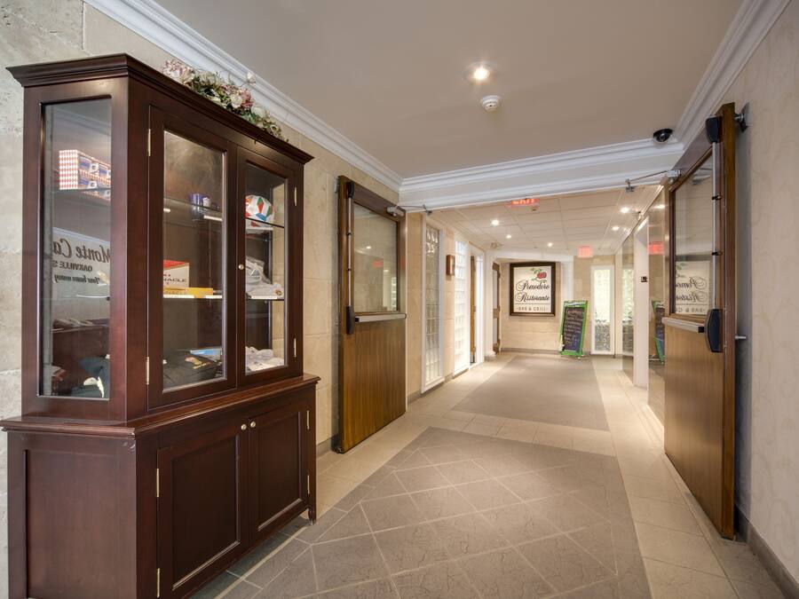 A hotel corridor with a wooden display cabinet, a tiled floor, and a sign for the restaurant.