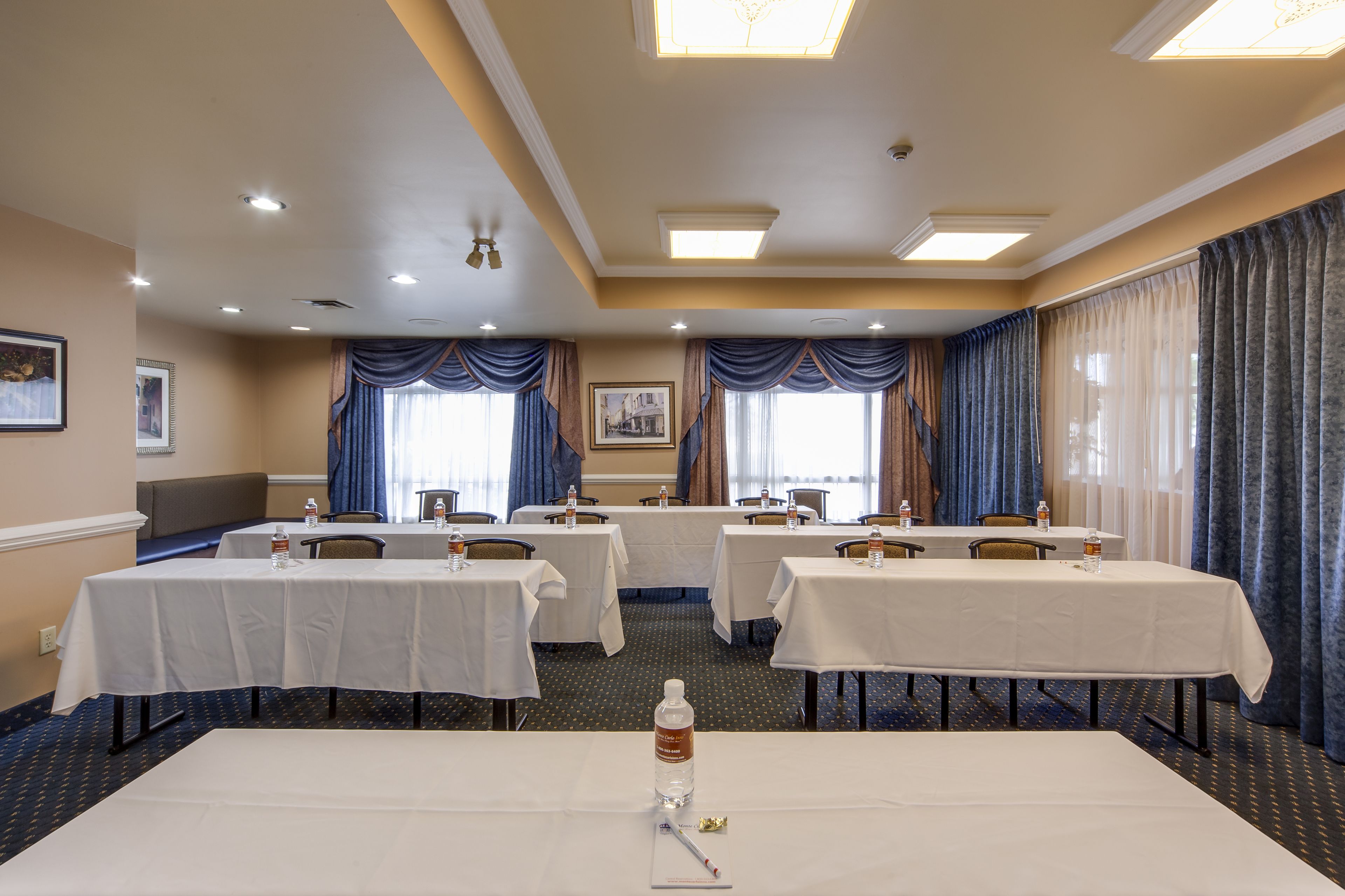 Un salón de conferencias con mesas, sillas y botellas de agua.
