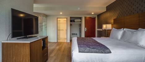 A hotel room with a bed, a TV, a wardrobe, and a bathroom visible through an open door.