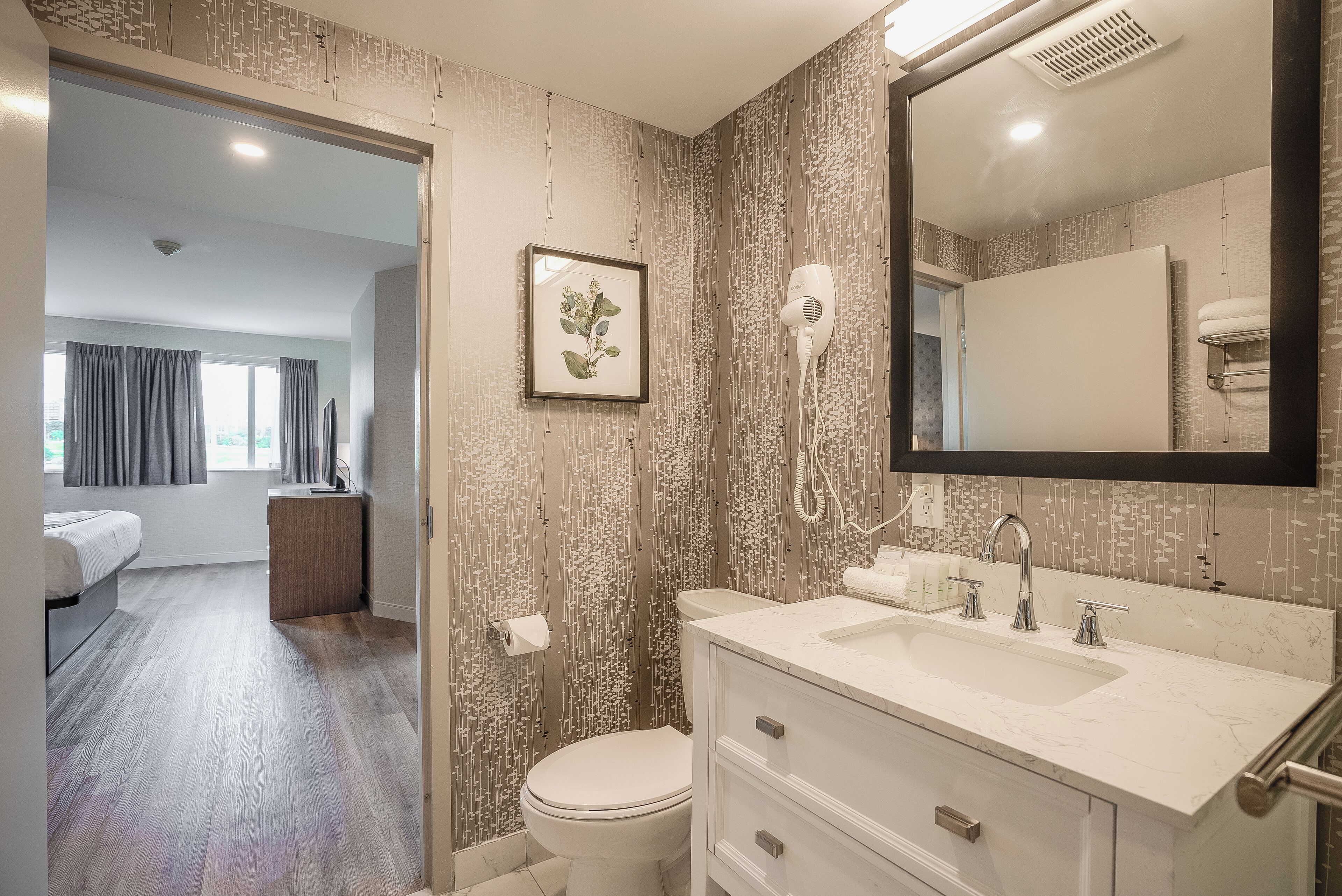 Une salle de bain moderne avec un grand miroir, un sèche-cheveux et des toilettes.