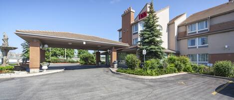 L’entrée d’un hôtel, avec un espace de stationnement couvert, une statue et un sapin de Noël.