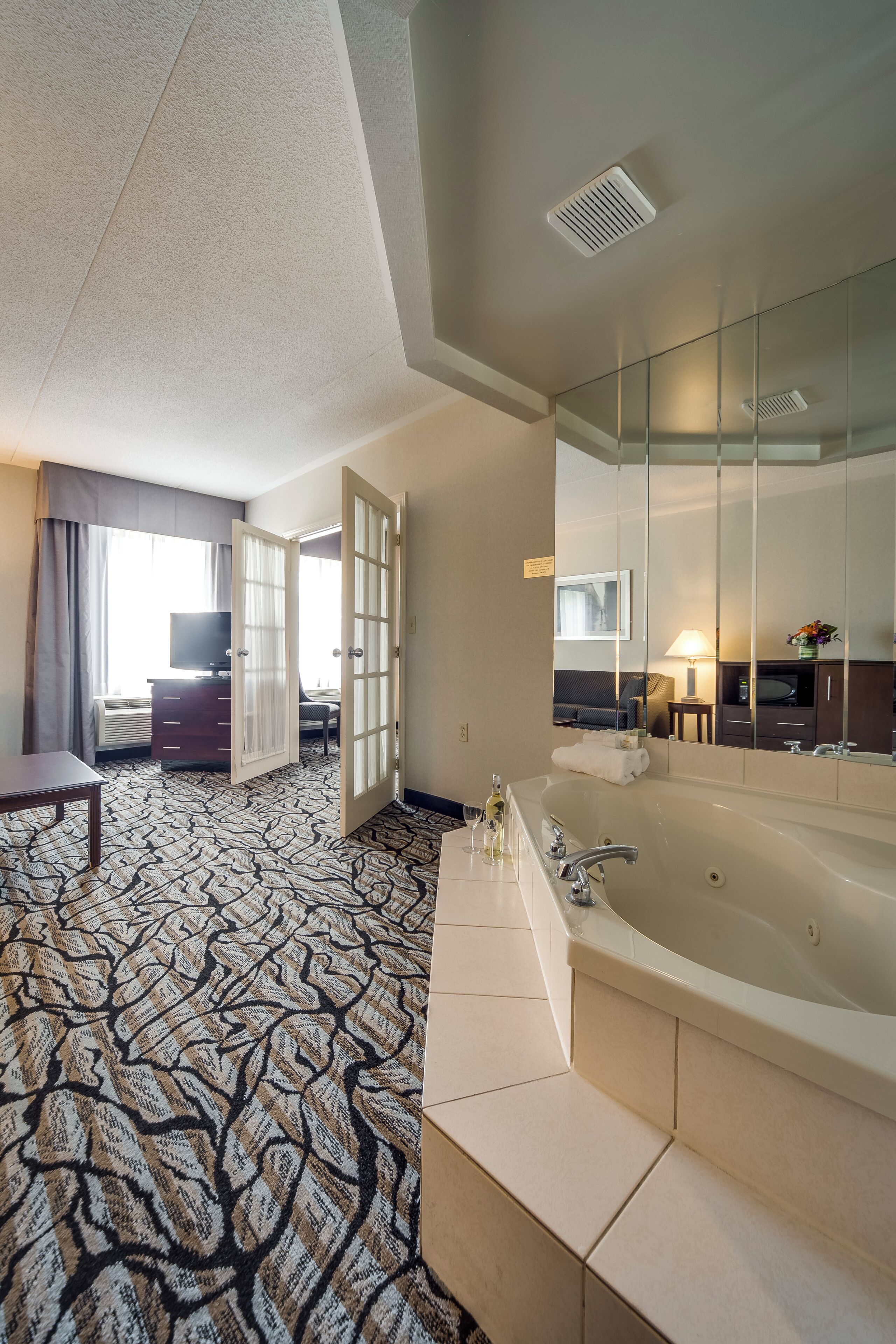 Een hotelkamer met een groot bad, een televisie, een bureau en uitzicht op de omgeving.