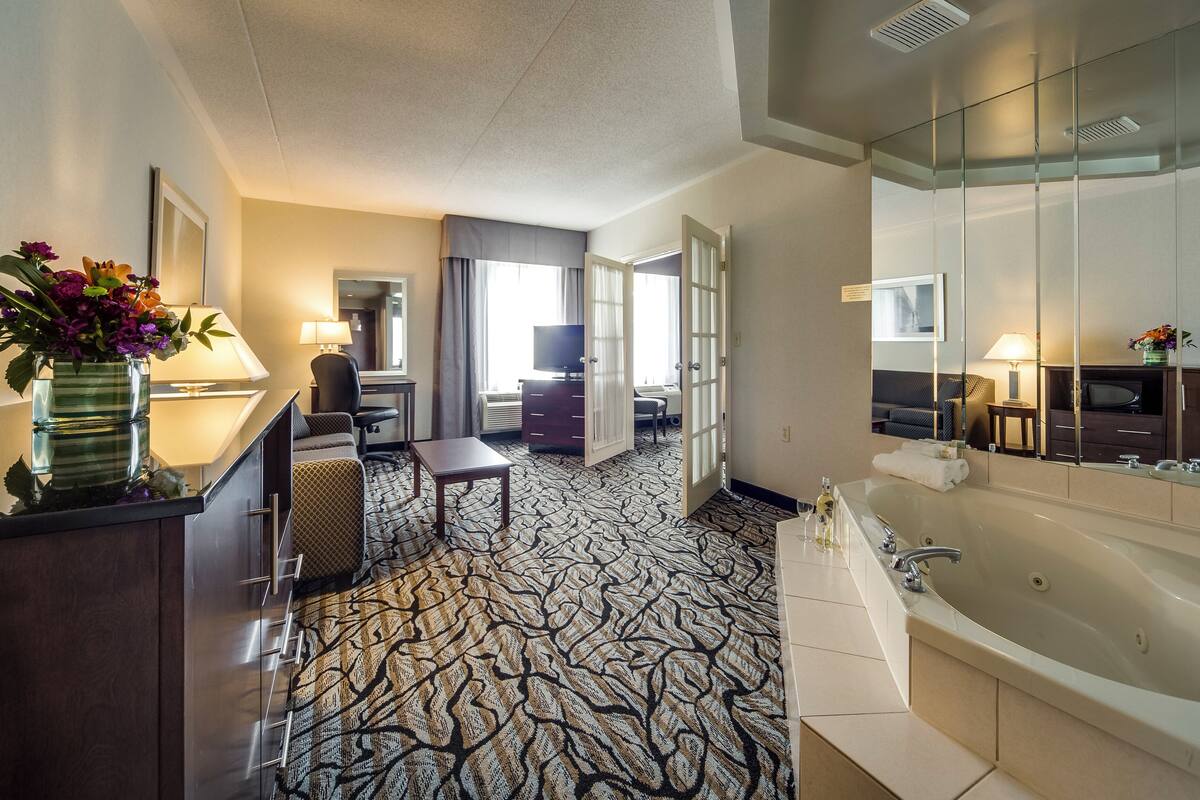 Une chambre d’hôtel avec une grande baignoire, un bureau avec une chaise, une petite table et un miroir.