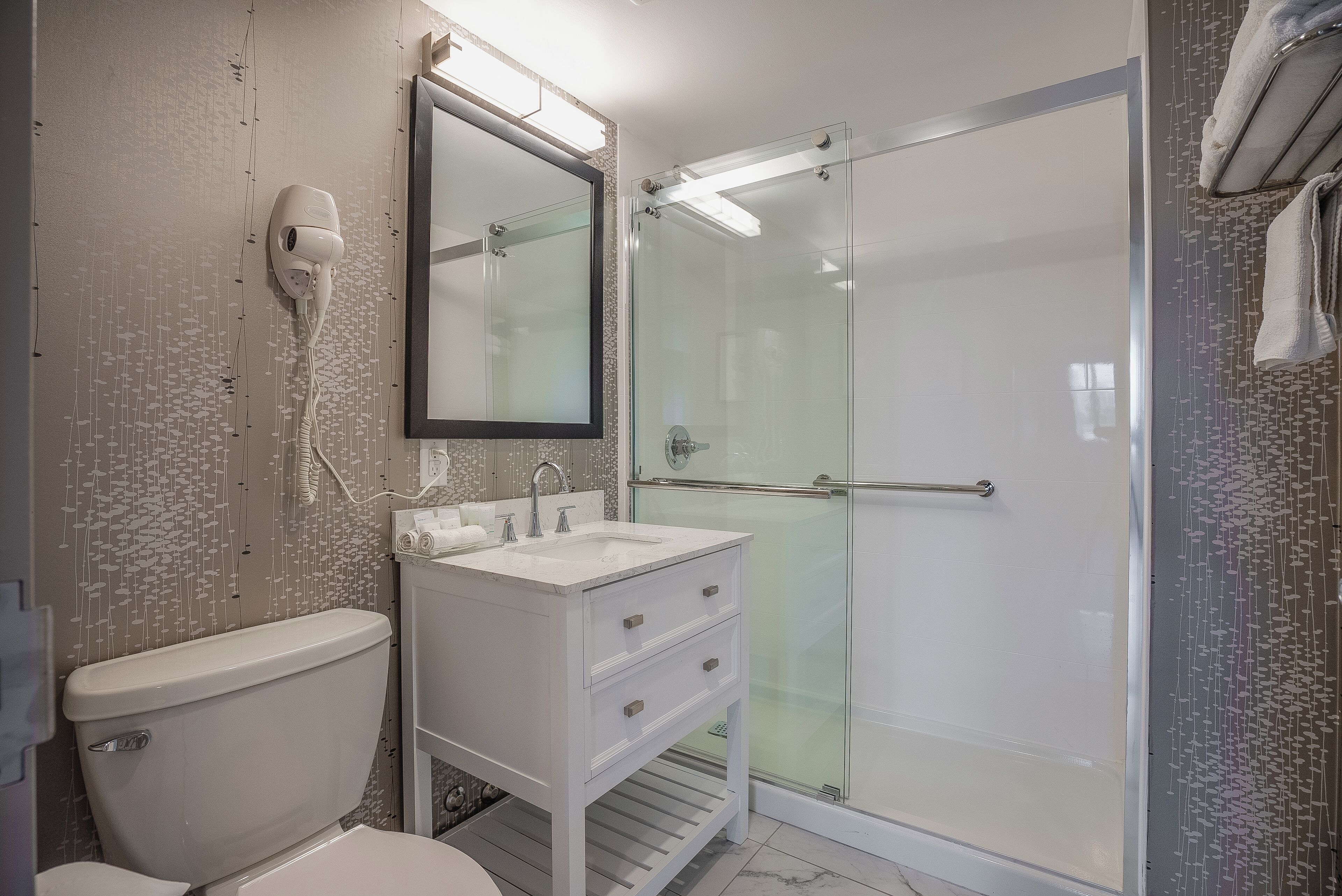 Ein Badezimmer mit Toilette, Waschbecken mit Spiegel und einer Duschkabine.