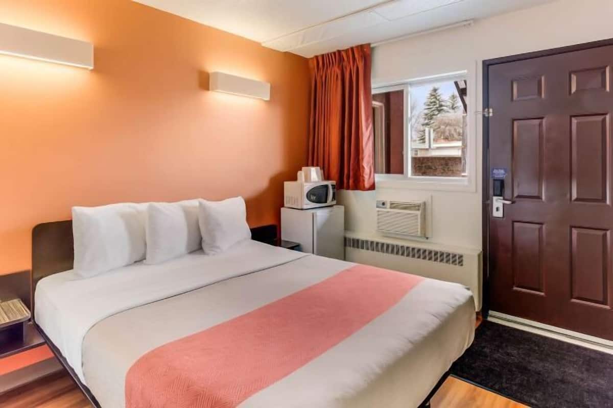 Una habitación de hotel con una cama, microondas, calefacción y una puerta.