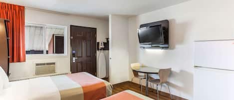 Habitación de hotel con dos camas, televisor, escritorio y una silla.