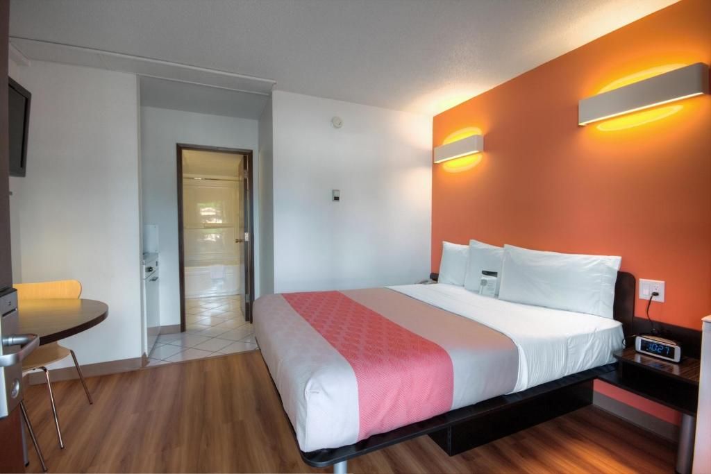 A hotel room with a bed, bedside table, and a small table with chairs.