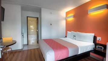 A hotel room with a bed, bedside table, and a small table with chairs.
