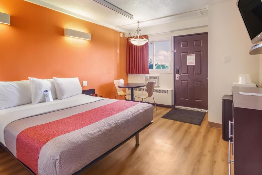 Ein Hotelzimmer mit Bett, Schreibtisch, Stuhl, kleinem Tisch und einer Tür.