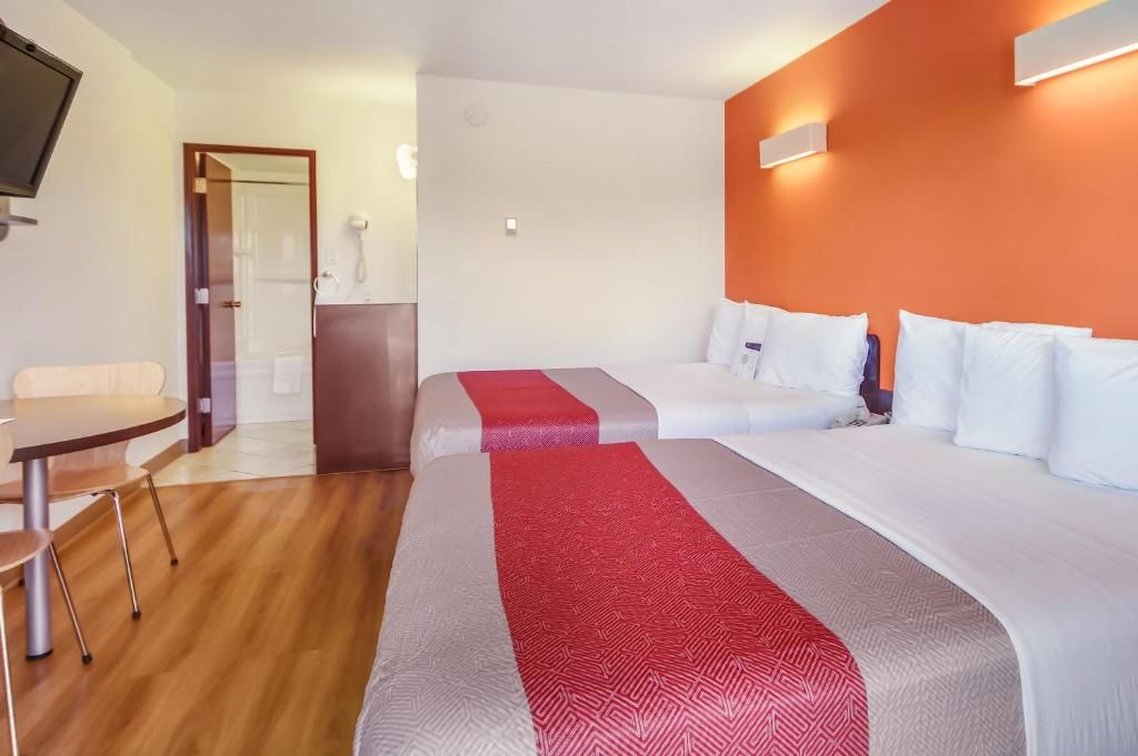 A hotel room with two beds, a desk, and a chair.