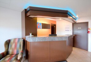 A reception desk with a number sign, a chair, and a fire extinguisher.