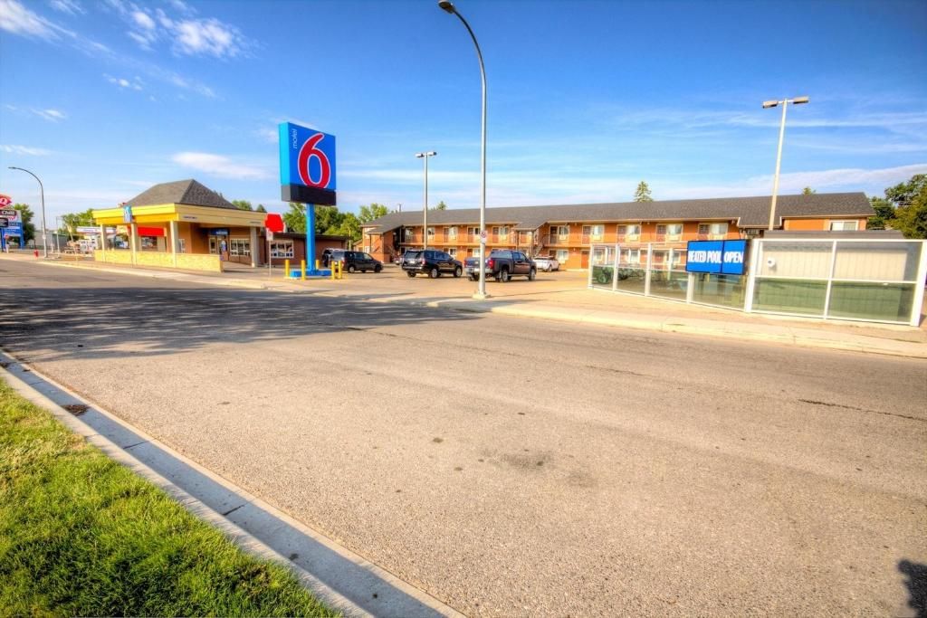 A 6-star hotel with a large sign, parking lot, and a building with multiple windows.