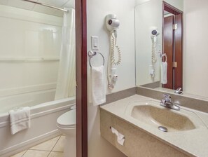 A bathroom with a bathtub, toilet, and a sink with a mirror.