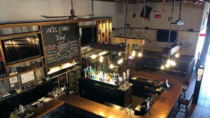 A bar area with a chalkboard sign, bar stools, and a variety of bottles. - Petawawa River Inn and Suites (Petawawa)