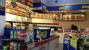 A Greco Pizza restaurant interior with a counter, menu boards, and shelves stocked with sodas and snacks. - Petawawa River Inn and Suites (Petawawa)
