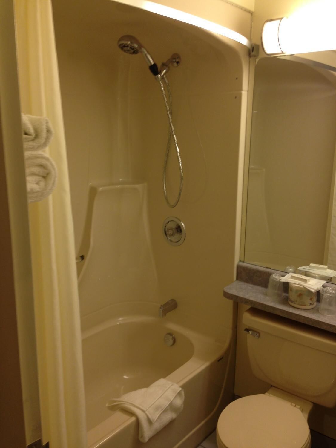 Et badeværelse med badekar, toilet og håndvask med toiletartikler.