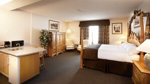 A hotel room with a bed, a desk with a sink, a chair, a lamp, and a plant. - Petawawa River Inn and Suites (Petawawa)