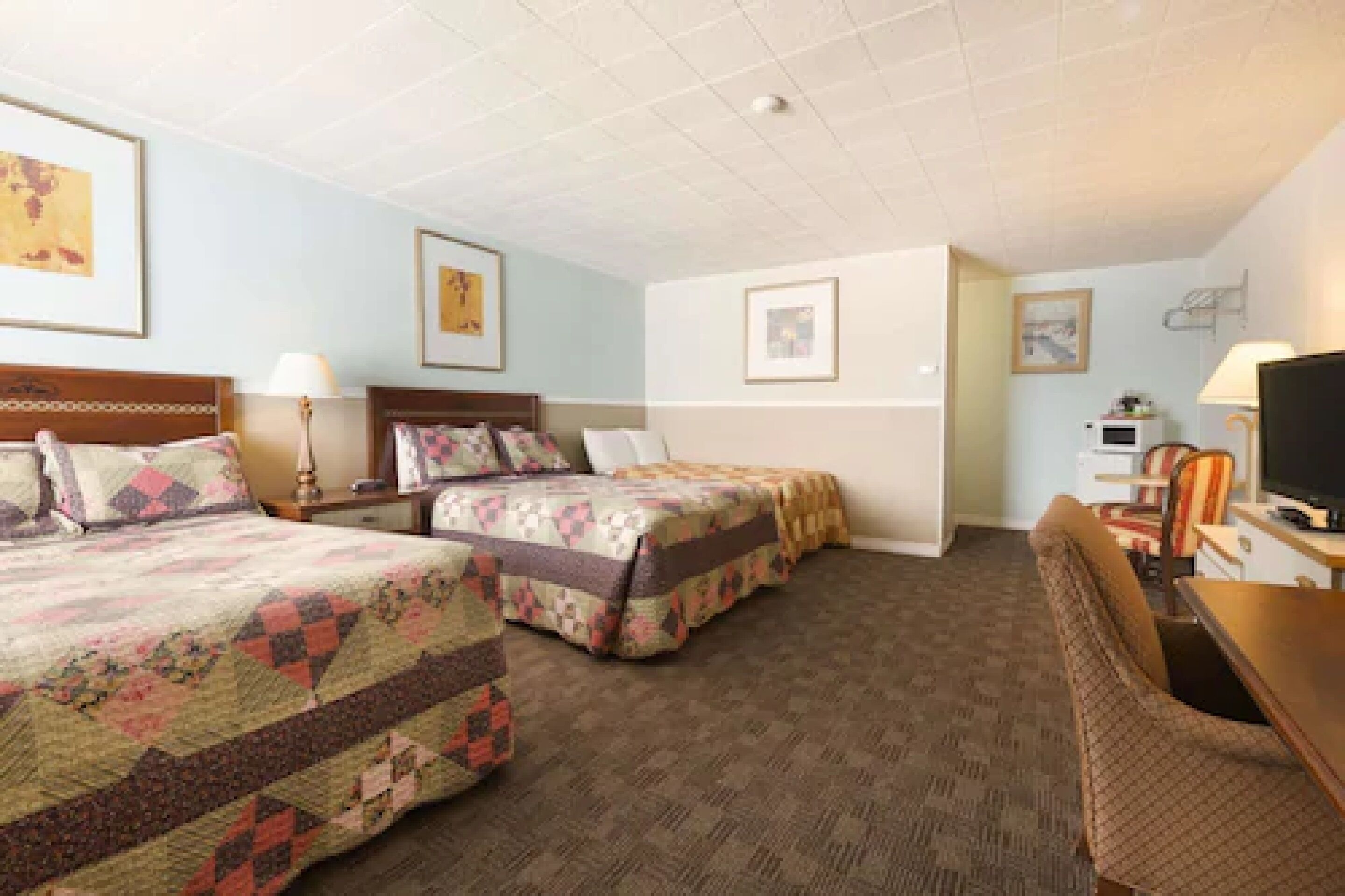 Een hotelkamer met twee bedden, een bureau, een stoel en een televisietoestel.