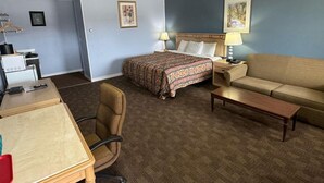 Una habitación de hotel con una cama, un sofá, un escritorio y una silla.