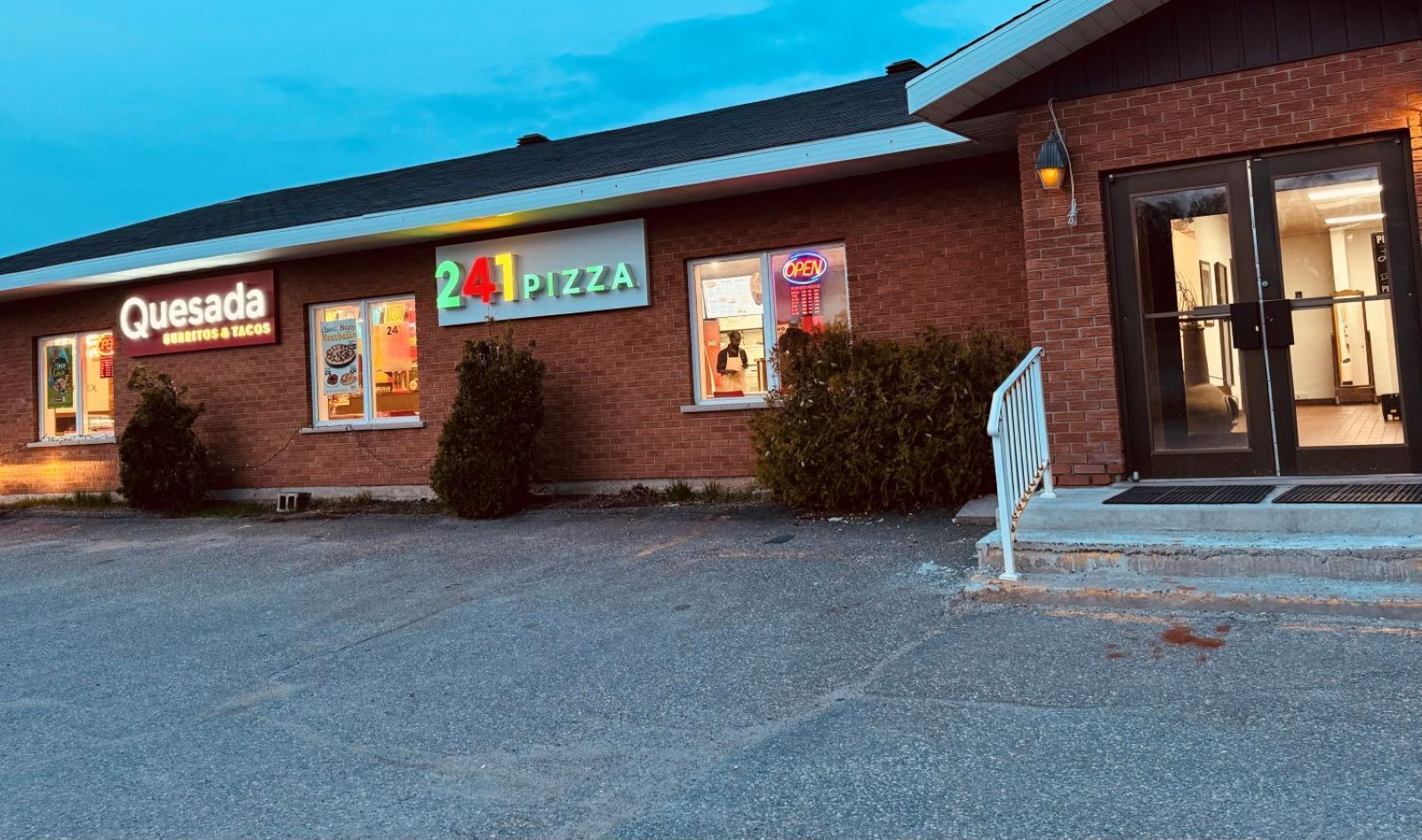 Een bakstenen gebouw met een bordje waarop 'Quesada Burritos & Tacos' en '241 Pizza' staat.