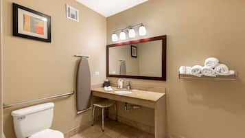 A bathroom with a toilet, sink, mirror, towel rack, and a framed picture on the wall.