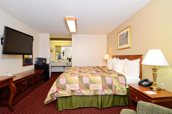 A hotel room with a bed, a desk, a television, a lamp, and a telephone.